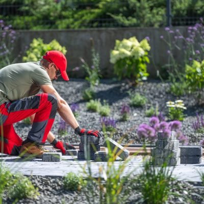 Gardener Laying Stones for a Pathway in a Blooming Flower Garden on a Sunny Day